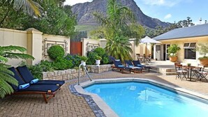 A pool area with lounge chairs and a view of a mountain. - Grande Plaisir Holiday Home (Franschhoek)