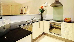 Eine moderne Küche mit schwarzem Arbeitsplatz, weißen Schränken, einer Edelstahl-Spüle und einem eingebauten Backofen.