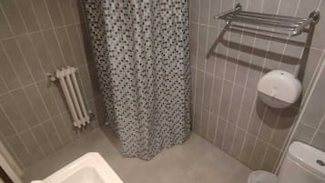 A bathroom with a shower, a sink, a toilet, and a towel rack.