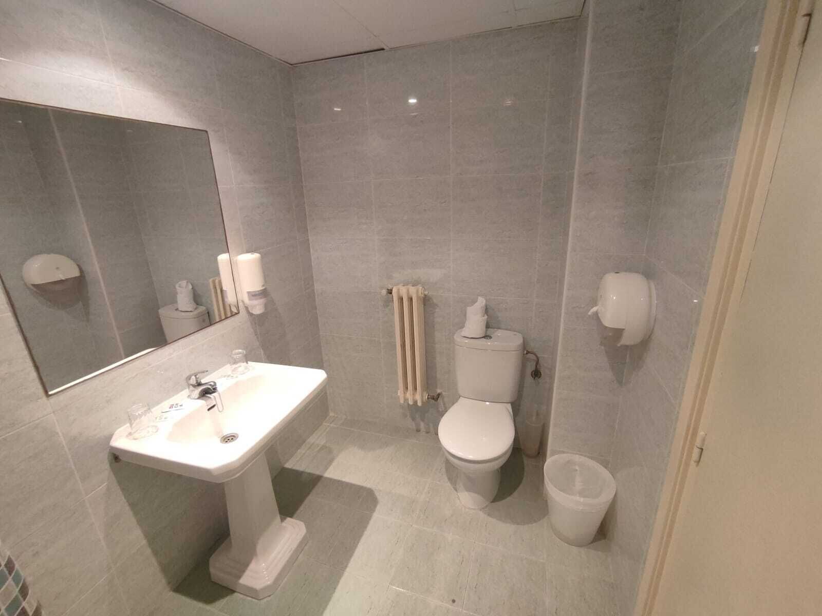 Ein modernes Badezimmer mit einem Standwaschbecken, einer Toilette, einem Bidet und einem Händetrockner.