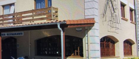 A building with a sign reading "Ria Restaurante" and outdoor seating with chairs.