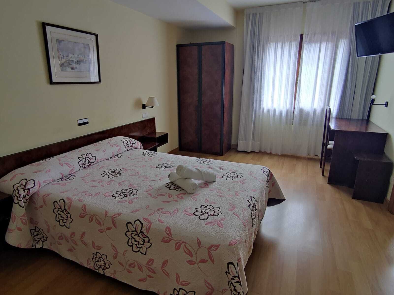 Een hotelkamer met een bed, een bureau, een kledingkast en een schilderij aan de muur.