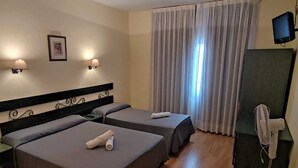 A hotel room with two beds, a desk, a chair, a television, and a window with curtains. - Hotel El Molino de Pancorbo (Pancorbo)