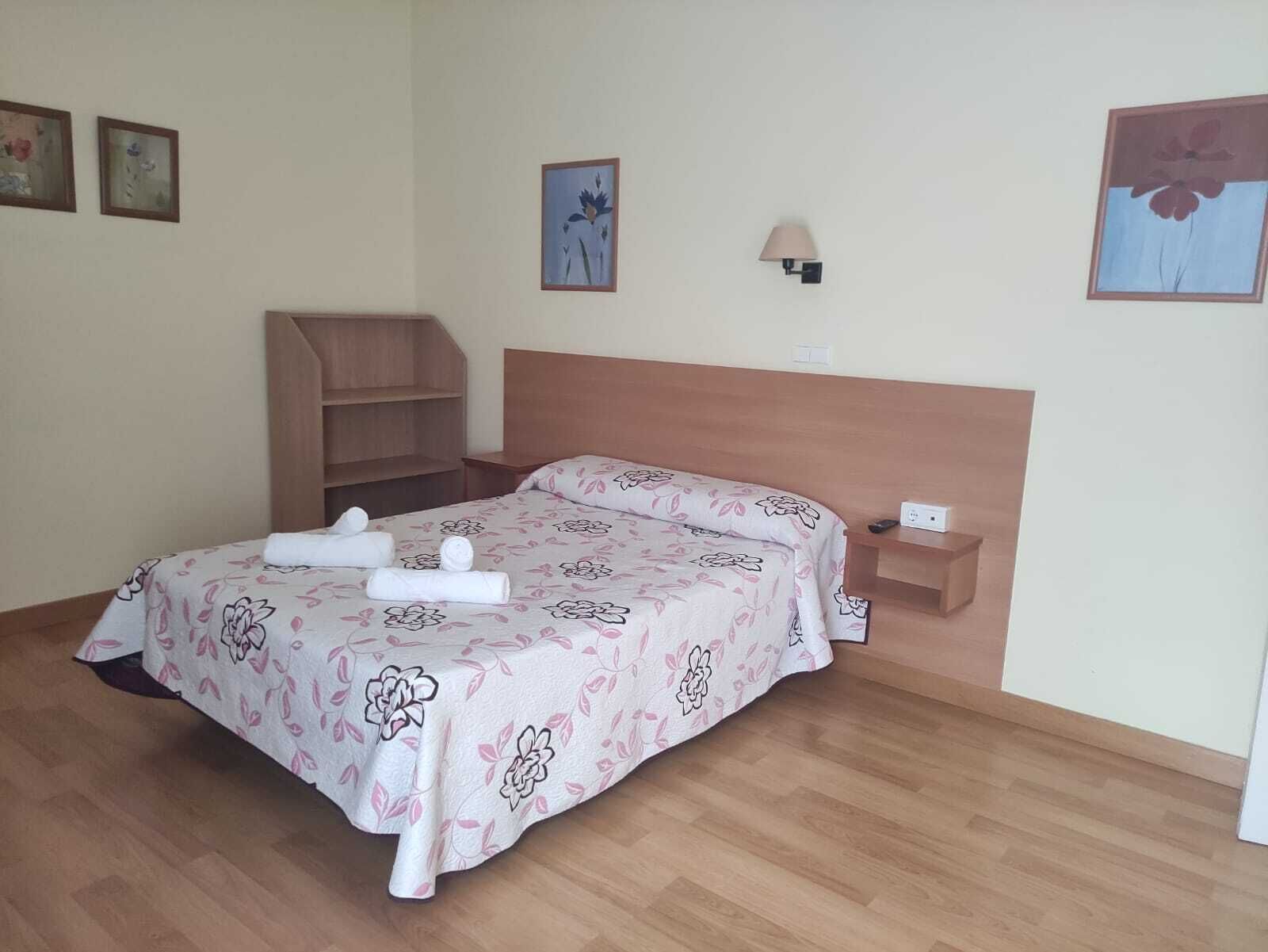 Ein Hotelzimmer mit einem Bett, einem Nachttisch, einer Lampe und einem Holzregal.