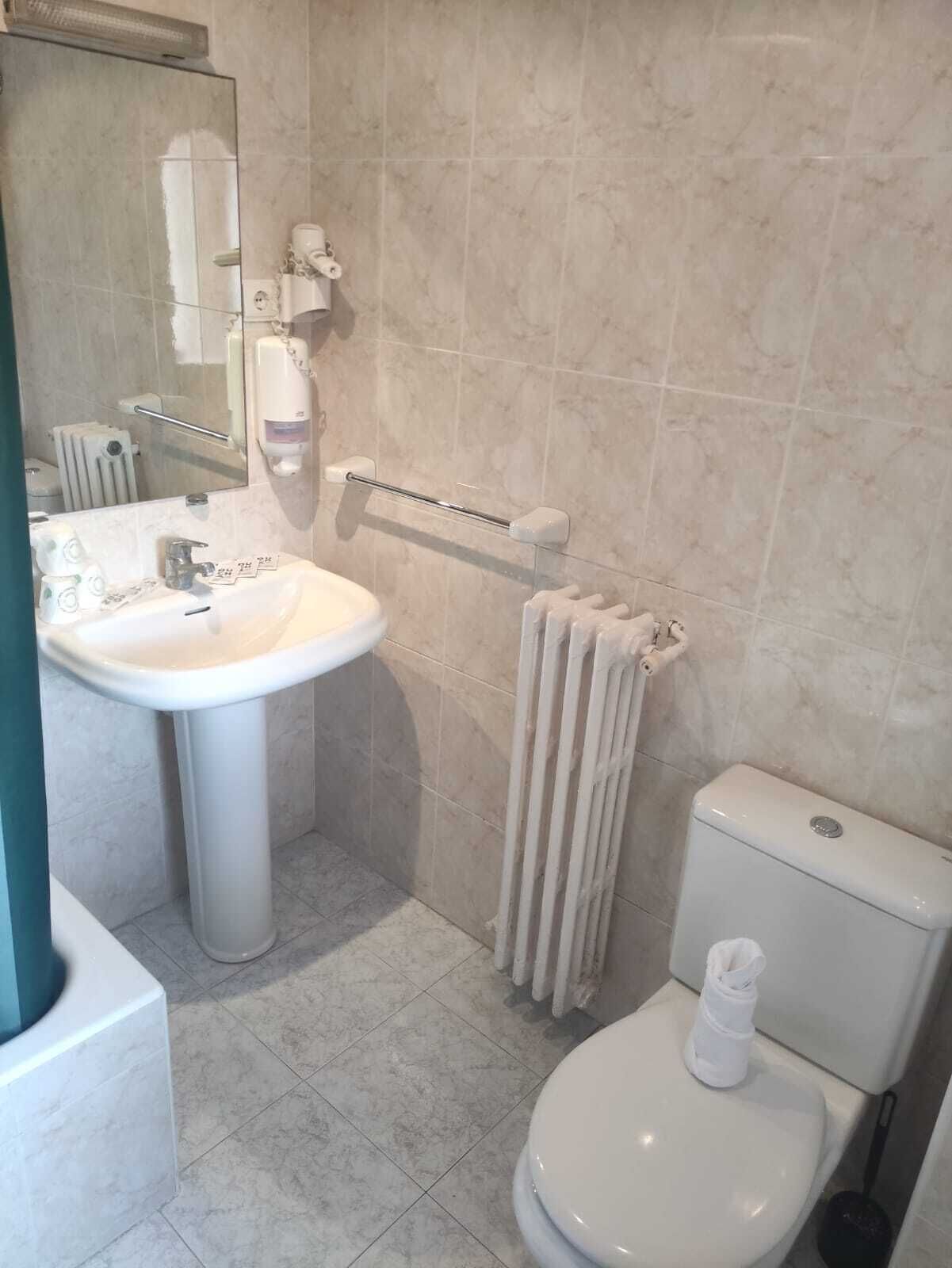 Un baño con lavamanos, inodoro y perchero para toallas.
