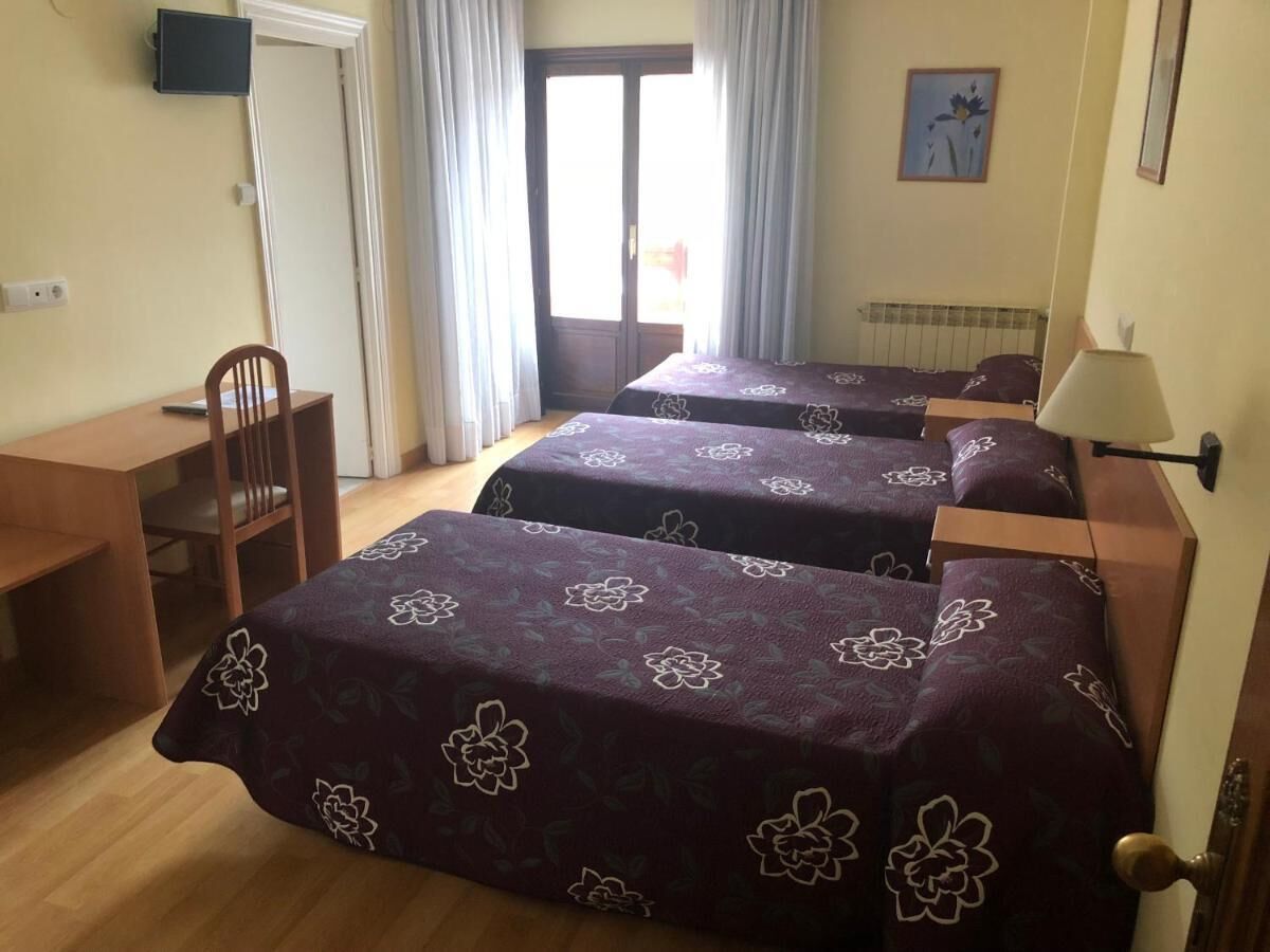 Una habitación de hotel con tres camas, un escritorio y una silla.
