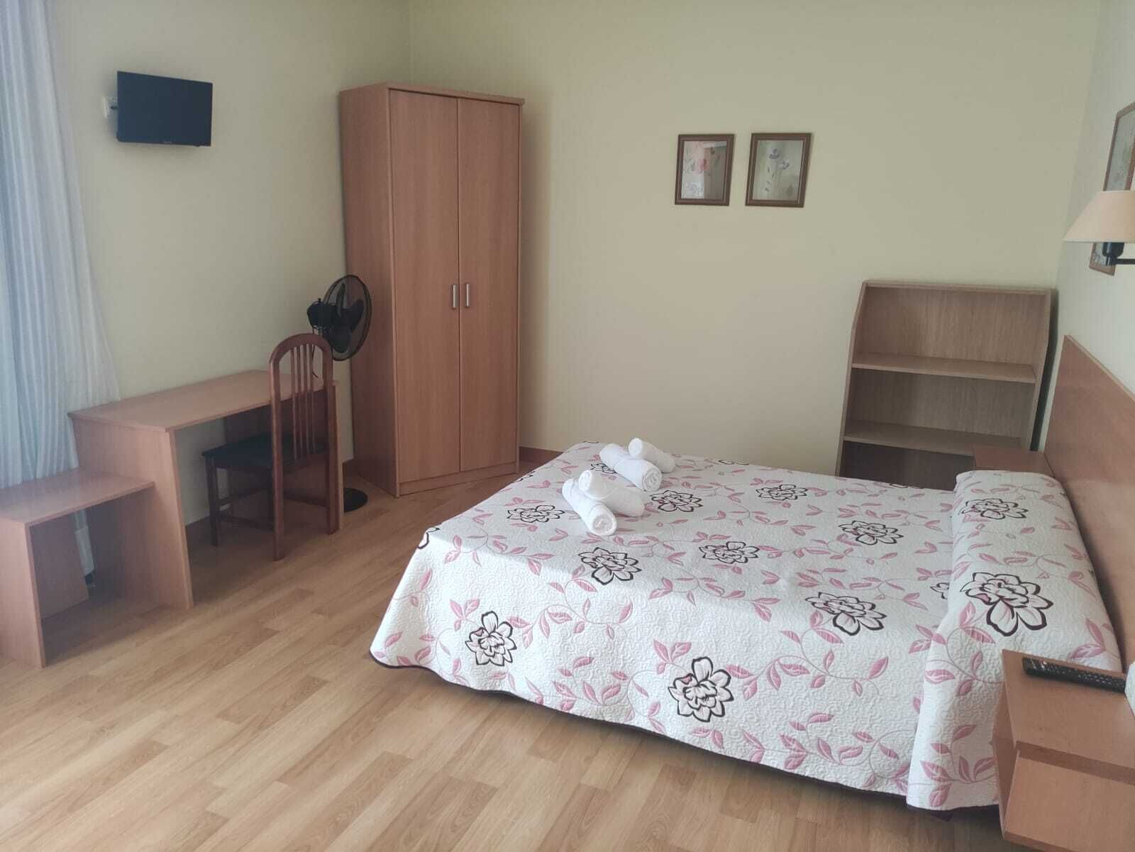 A bedroom with a bed, a desk, a wardrobe, and a chair.
