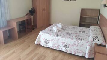 A bedroom with a bed, a desk, a wardrobe, and a chair.