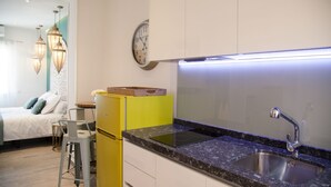 A modern kitchen with a built-in stove, a sink, and a clock on the wall. - Suites Miguel Ángel - Adults Only (Madrid)