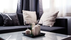 A modern living room with a glass coffee table, a sofa with dark cushions, and decorative candles. - Suites Miguel Ángel - Adults Only (Madrid)