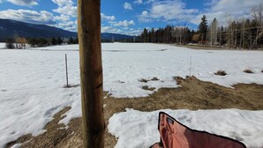 Un campo nevado con un poste de madera y un objeto rojo, posiblemente una silla, en primer plano.