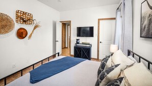 A bedroom with a bed, a TV, a bedside table, and a door leading to another room. - Pet-Friendly Cabin | River Access, Grill & Firepit (Kyle)