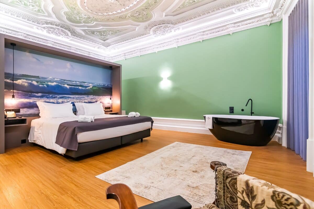 A modern bedroom with a bed, a large wall mural, a bathtub, and a wooden floor.