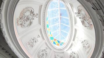 A ceiling with a central skylight and ornate moldings.