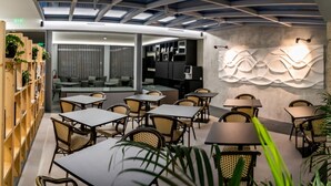 A modern indoor space with a glass ceiling, wooden bookshelves, and tables with chairs. - Flag Design Hotel (Viana do Castelo)