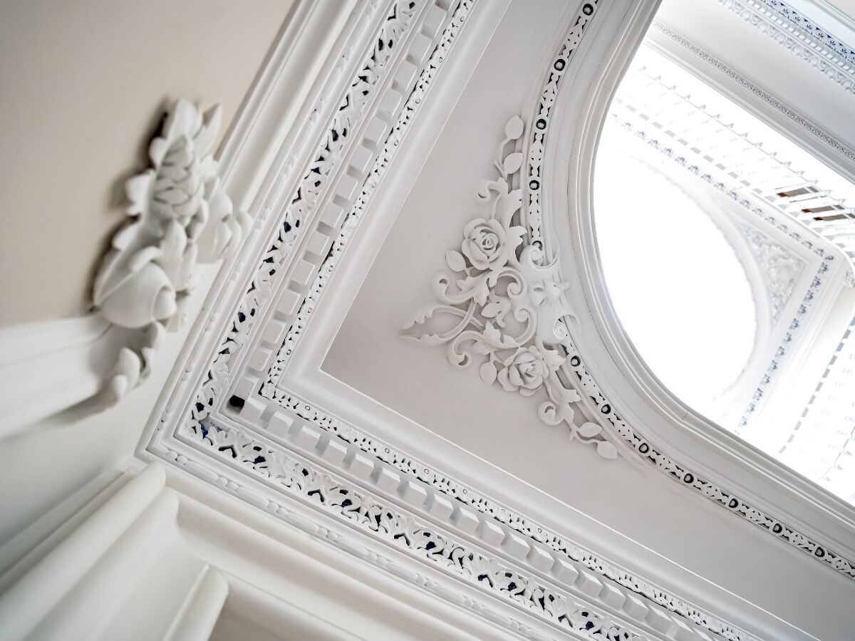 Un plafond richement décoré, orné de motifs floraux sculptés, et une lucarne.