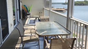 A covered outdoor area with a table and chairs, a ceiling fan, and a view of a body of water.
