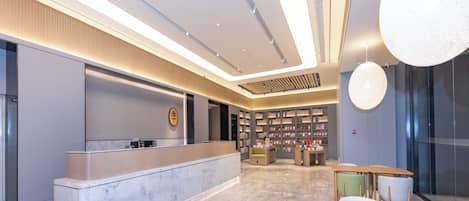 Un moderno vestíbulo de hotel con mostrador de recepción, zona de estar y una biblioteca.