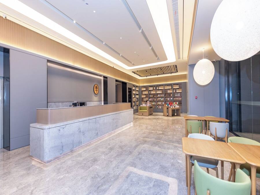 A modern hotel lobby with a reception desk, seating area, and a library.