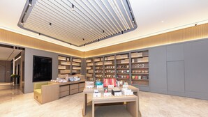 A modern interior with a central display table, bookshelves, and a seating area. - Ji Hotel (Nanjing)