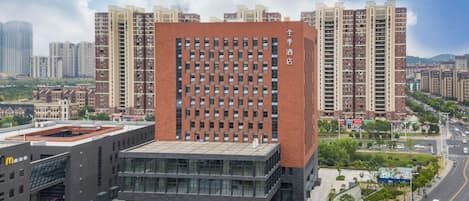 A modern hotel with a prominent red facade, multiple floors, and a central courtyard.