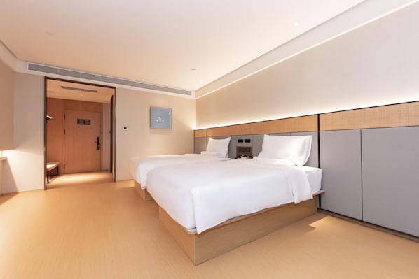 A hotel room with a double bed, a bedside table, a wardrobe, and a door leading to a hallway. - Ji Hotel (Nanjing)