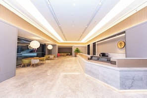 A modern hotel lobby with a reception desk, seating area, and a large window. - Ji Hotel (Nanjing)
