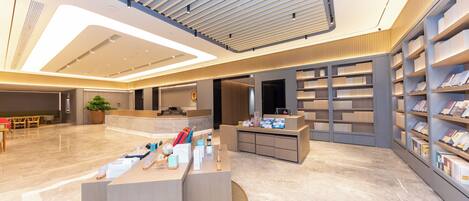 A modern interior with a reception desk, bookshelves, and a seating area.
