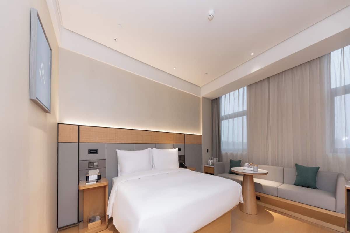 Ein modernes Hotelzimmer mit einem großen Bett, Nachttischen, einer Couch und einem kleinen Tisch.