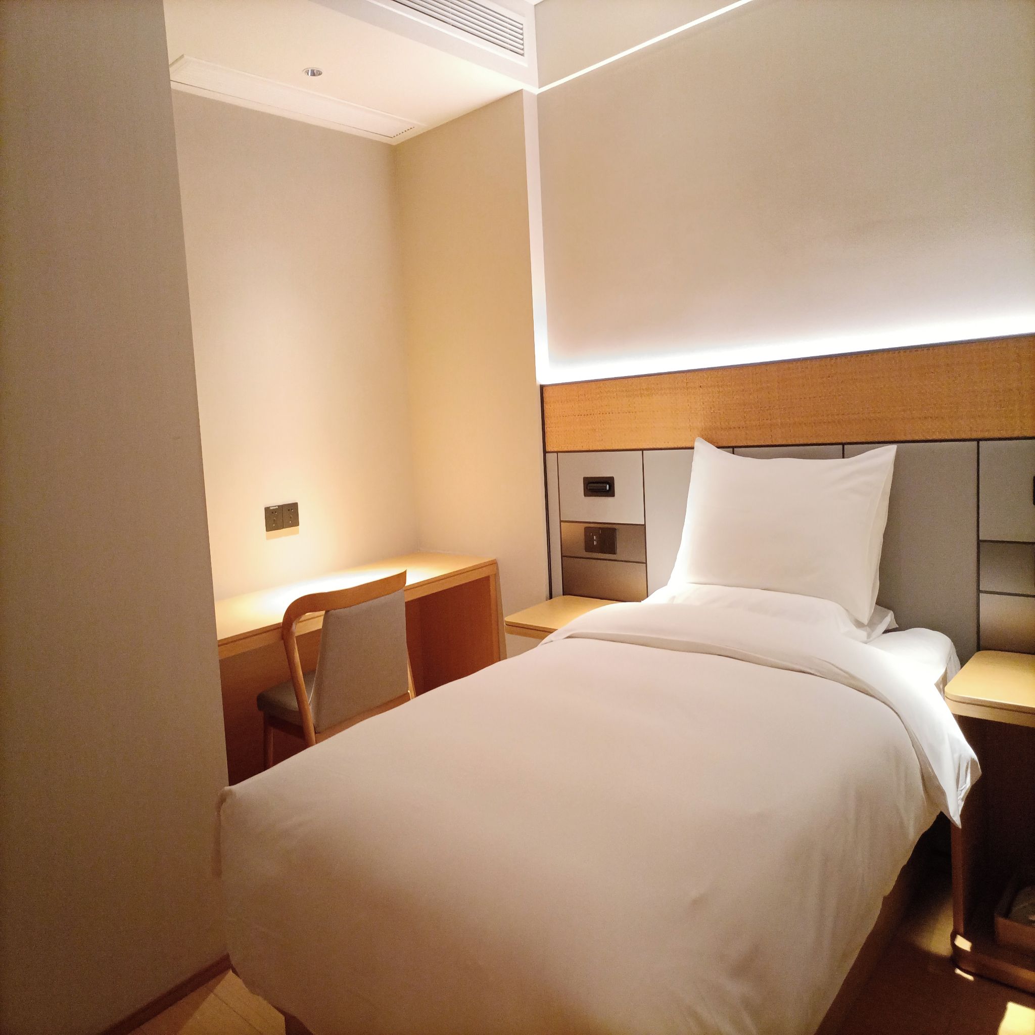 Quarto de hotel com uma cama, uma escrivaninha e uma cadeira.