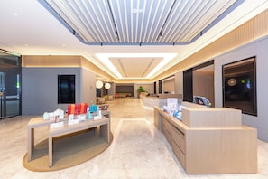 A modern hotel lobby with a reception desk, seating area, and a large window. - Ji Hotel (Nanjing)