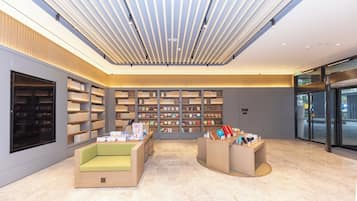 A modern library interior with bookshelves, seating areas, and a ceiling with linear light fixtures.