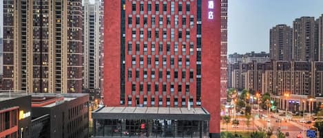 Een modern gebouw met een rode gevel en een grote glazen ingang.