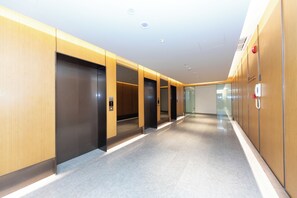 A modern hallway with elevators and a fire alarm on the wall. - Ji Hotel (Nanjing)