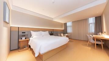 A modern hotel room with a large bed, bedside tables, a desk, and a chair.