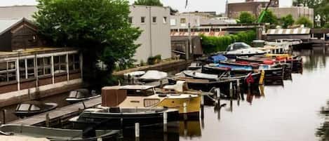 Un puerto deportivo con varias embarcaciones amarradas a lo largo de una vía fluvial tranquila, rodeado de edificios y vegetación.
