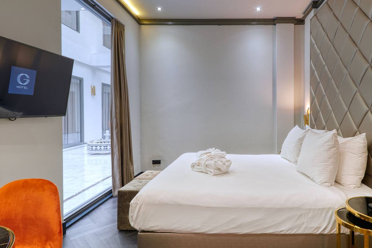 A hotel room with a bed, a TV, a window, and a view of the outside.