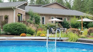 A swimming pool with a ladder, surrounded by a patio area with outdoor furniture and umbrellas. - Large private retreat (Union)