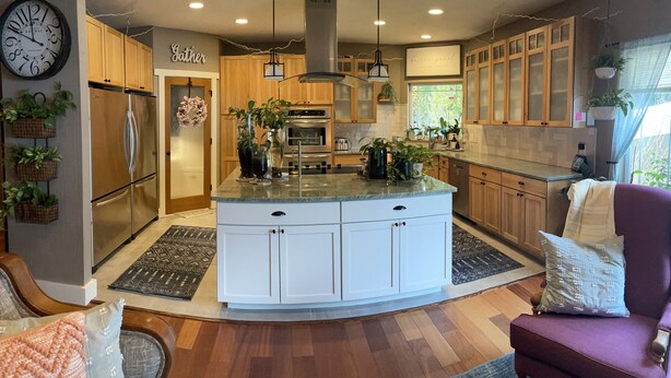 A modern kitchen with wooden cabinets, a central island, stainless steel appliances, and hanging plants. - Large private retreat (Union)