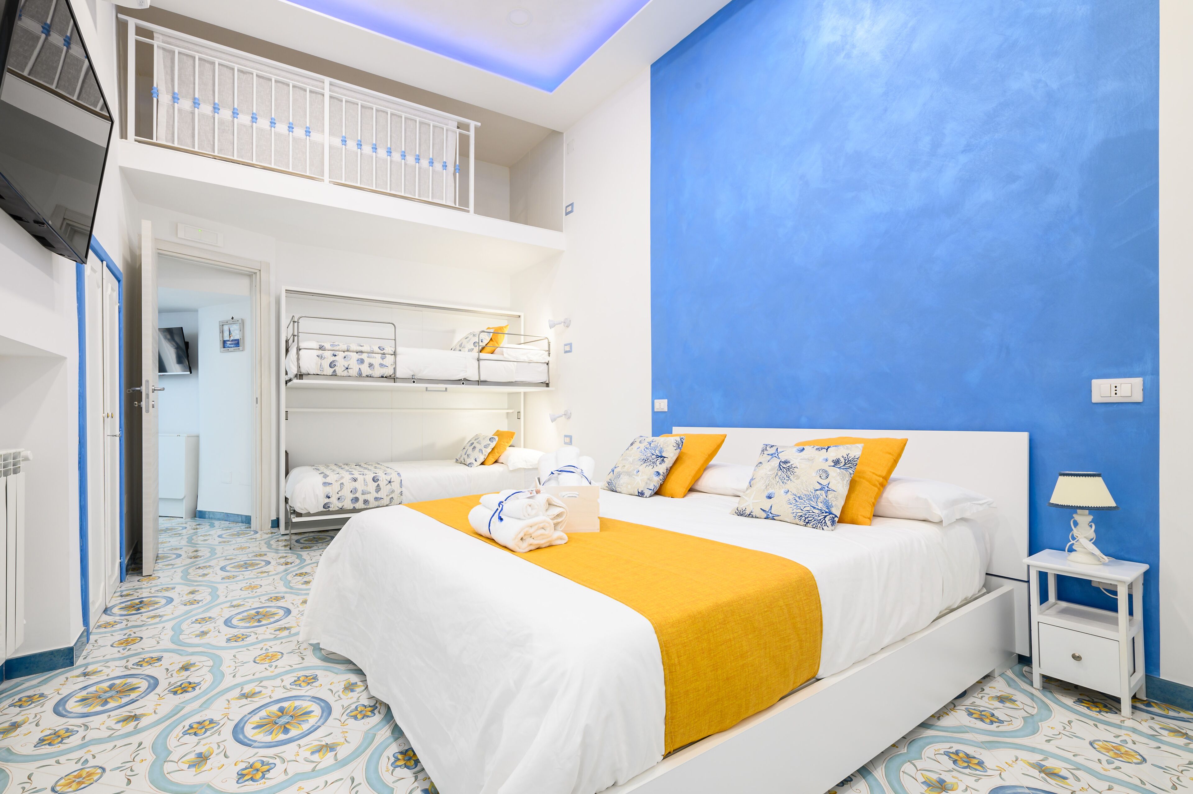 A hotel room with a large bed, a smaller bed, a balcony, and a patterned floor.