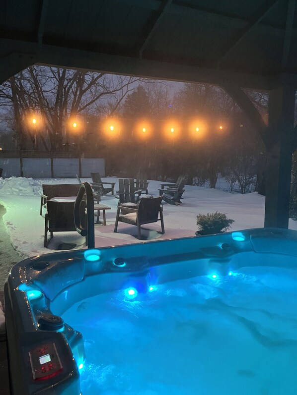 Ein Whirlpool mit blauen LED-Leuchten, umgeben von Gartenmöbeln und Schnee.