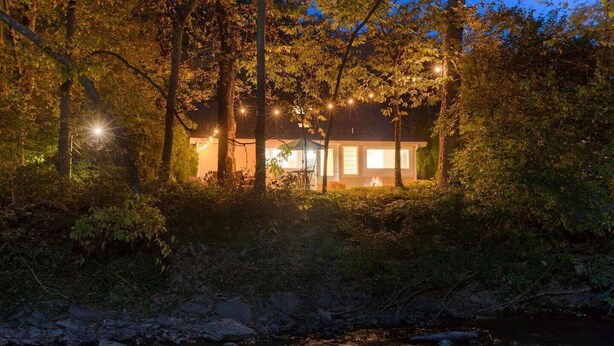 Una casa rodeada de árboles con luces colgantes.