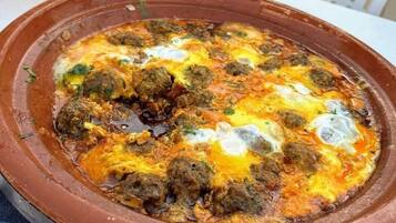 A clay dish with a meal, possibly a stew or casserole, on a table.