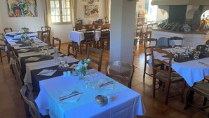 A restaurant with multiple dining tables set for service, featuring white tablecloths and wooden chairs. - Human Hotel Résidence  (Villecroze)