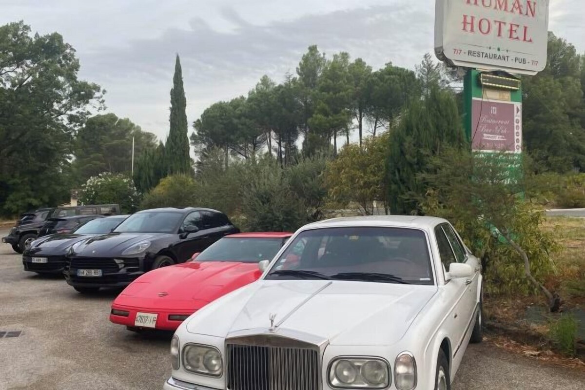 Un estacionamiento con coches de lujo, un cartel del Hotel Human y un restaurante.