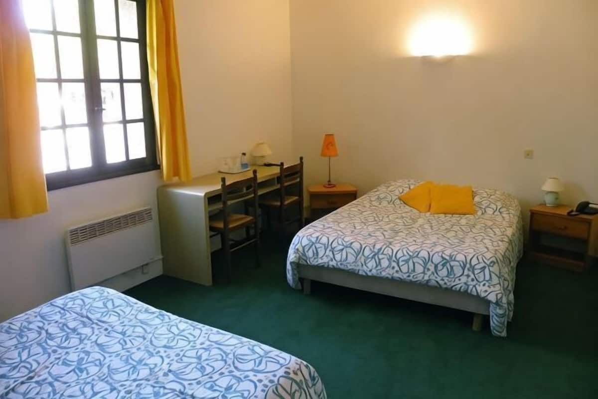 Ein Zimmer mit zwei Betten, einem Schreibtisch, einem Stuhl, einer Lampe und einem Heizgerät.