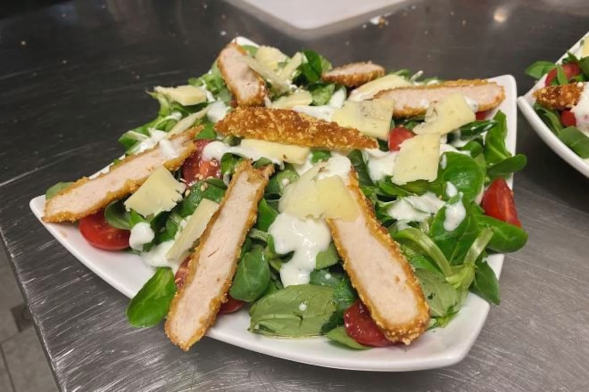 Ensalada con pollo, hojas verdes y aderezo cremoso.