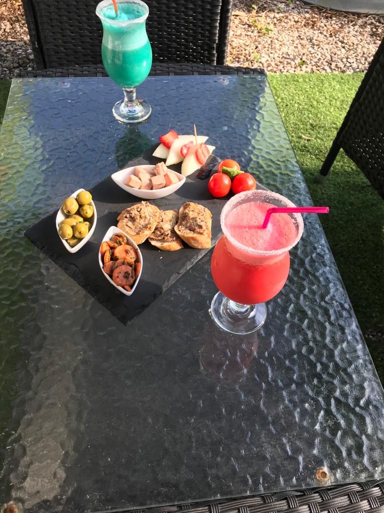 Ett bord med ett glas röd dryck, ett glas blå dryck och diverse snacks.