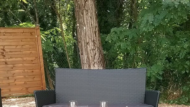 A wicker outdoor seating area with a glass table, two wine glasses, a fruit platter, and a decorative ball. - Human Hotel Résidence  (Villecroze)