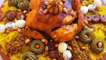 Uma travessa grande com frango assado, ovos, nozes e legumes.
